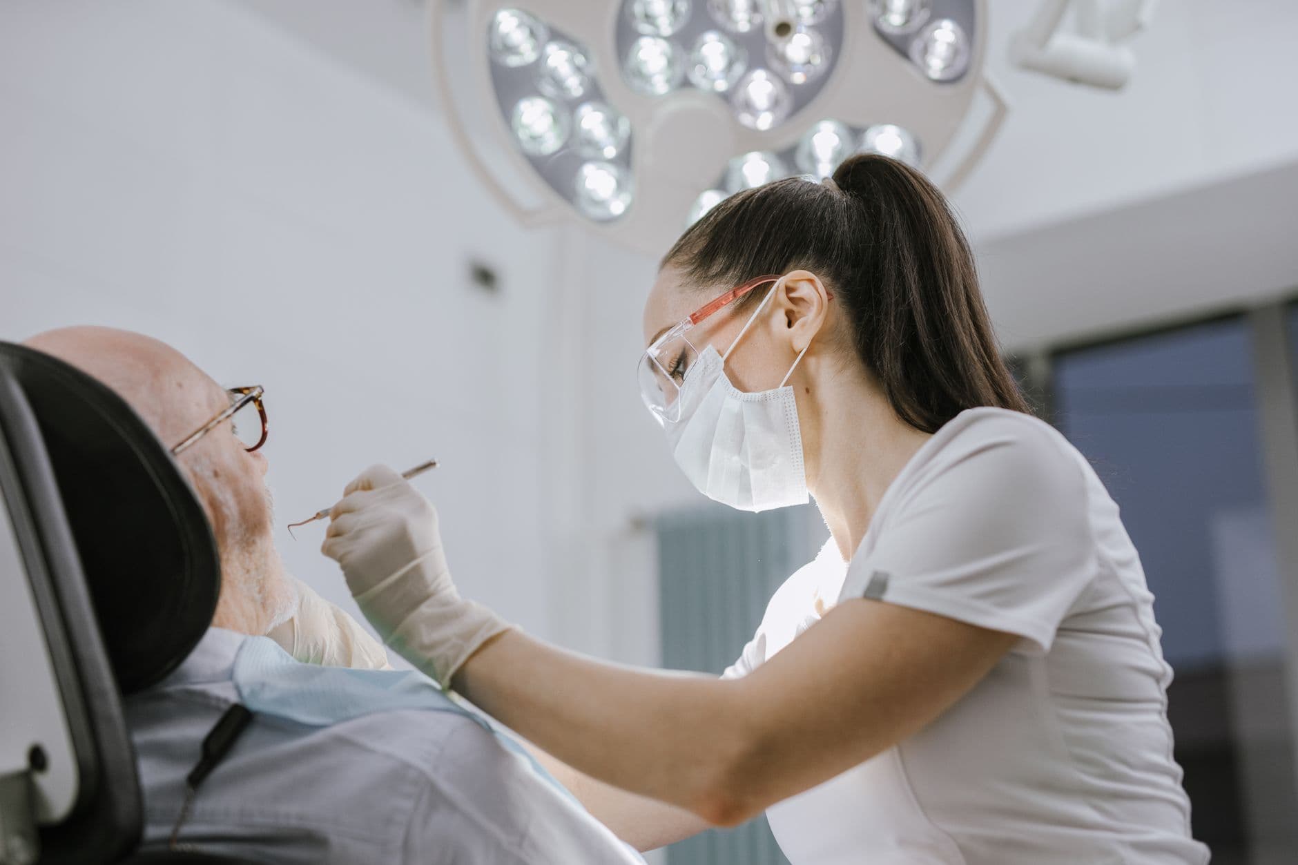 Female dentist working on a patient in a modern dental office with bright lighting.
