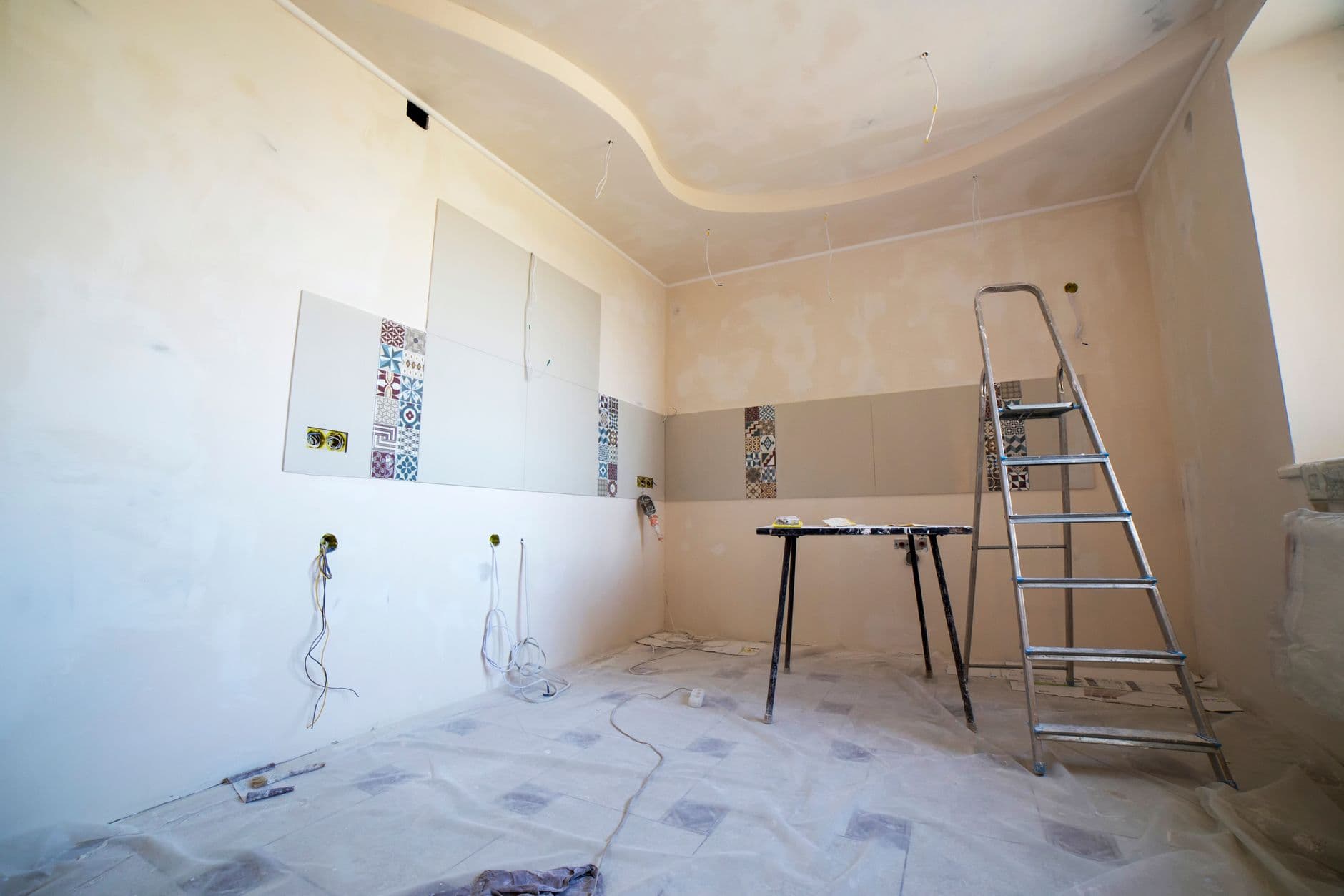 Interior view of a room under renovation with paint, tiles, and tools.